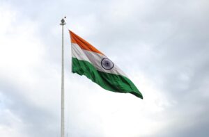 the flag of india on a flagpole under a cloudy sky